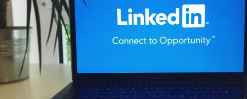 A laptop screen displaying the LinkedIn logo with the text 'Connect to Opportunity'.