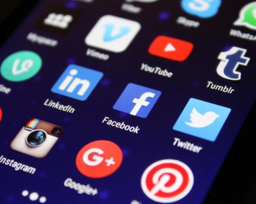 Close-up of a smartphone screen showing various social media app icons such as Facebook and Twitter.